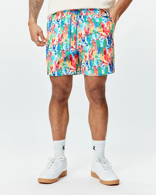 Mens Tanner Swim Trunk featuring a vibrant all-over print of colorful Psycho Bunny skull logos, crossbones, and abstract shapes, with a blue drawstring and a classic fit.