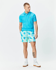 Bright blue pique polo with small embroidered Psycho Bunny skull logo on chest, paired with Mens Ethan Swim Trunk 6 featuring a light mint and blue abstract pattern and drawstring waist.