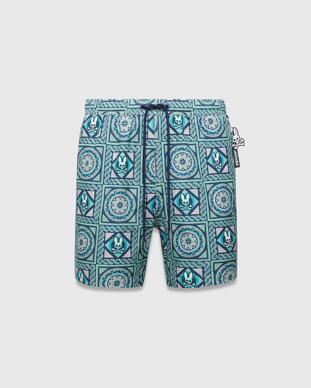 Mens Frank Swim Trunk 6, classic fit, vibrant teal, blue, and white mosaic tile pattern with repeated Psycho Bunny skull logos, floral motifs, dark blue drawstring, and a Psycho Bunny hip tag. (5)