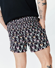 Mens Byron Swim Trunk 6, black with an all-over Psycho Bunny skull and crossbones pattern in pink, orange, mint green, and white, featuring a relaxed fit and smooth quick-dry fabric. (2)