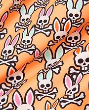 Mens Byron Swim Trunk 6, peach with an all-over print of the iconic Psycho Bunny skull logo, featuring white skulls with black outlines and alternating pink, mint green, and orange ear accents on smooth swim fabric.
