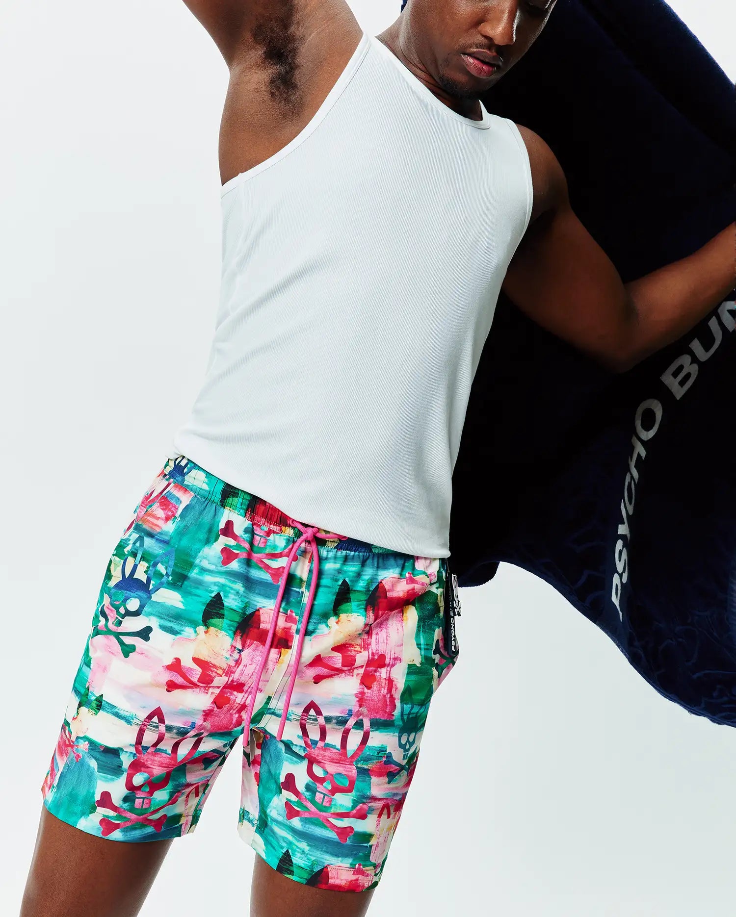Mens Nate All Over Print Swim Trunk, vibrant multi-color abstract pattern in teal, pink, red, green, with repeated Psycho Bunny skull and crossbones, relaxed fit, bright pink drawstring.