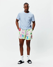 Light blue classic fit jersey t-shirt with small embroidered Psycho Bunny logo on left chest. Mens Quintin All Over Print Swim Trunk features an off-white base, vibrant multi-color graffiti-style bunny skull print, and neon green drawstring.