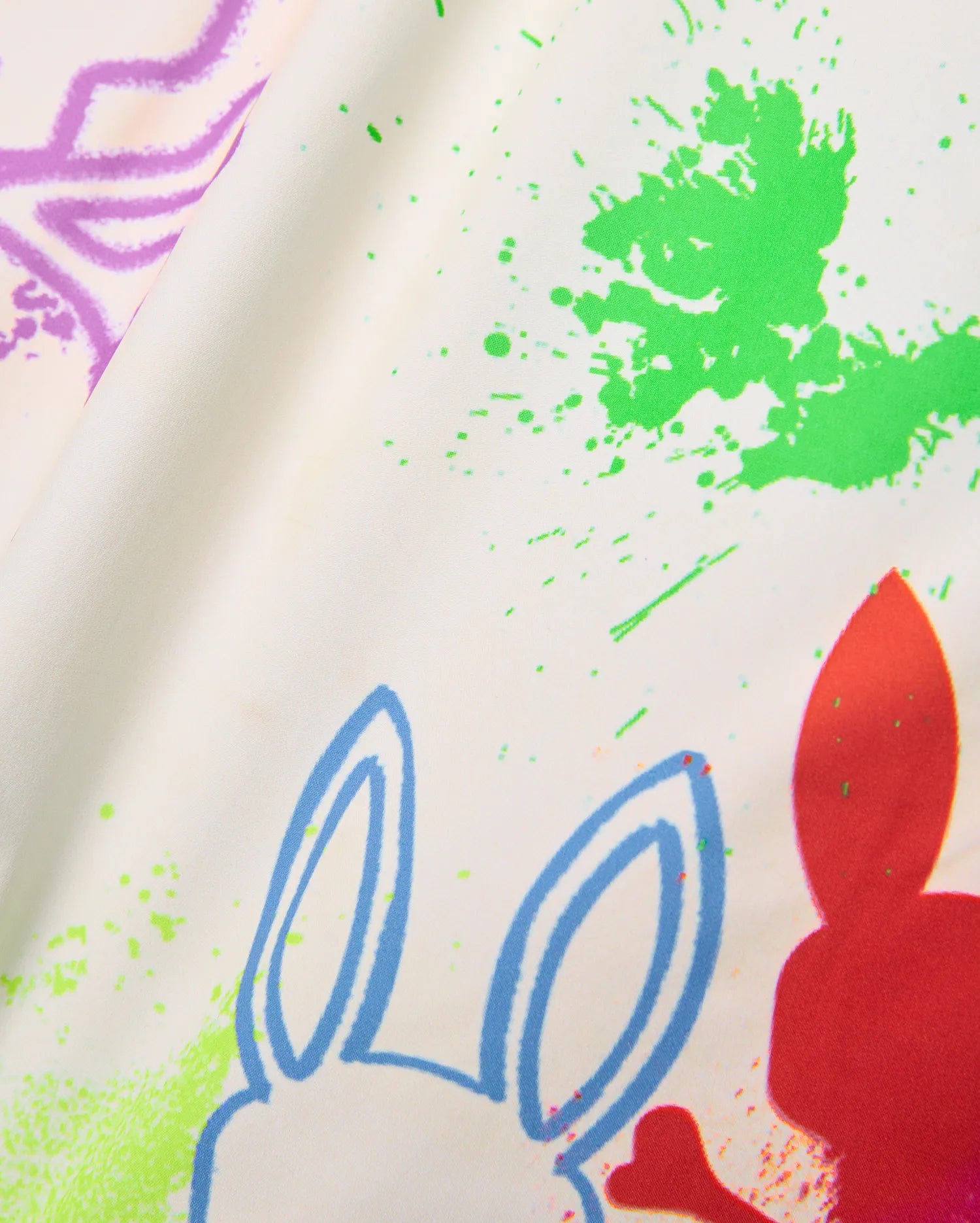 Mens Quintin All Over Print Swim Trunk, cream fabric with vibrant green, purple, blue, and red paint splatter print, featuring repeated Psycho Bunny skull outlines and solid shapes.