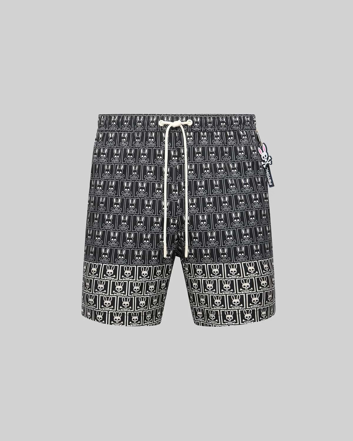 Mens Keon All Over Bunny Swim Trunk, black with an all-over white bunny skull logo pattern, classic fit, featuring a white drawstring and a small pink and white Psycho Bunny tag. (5)