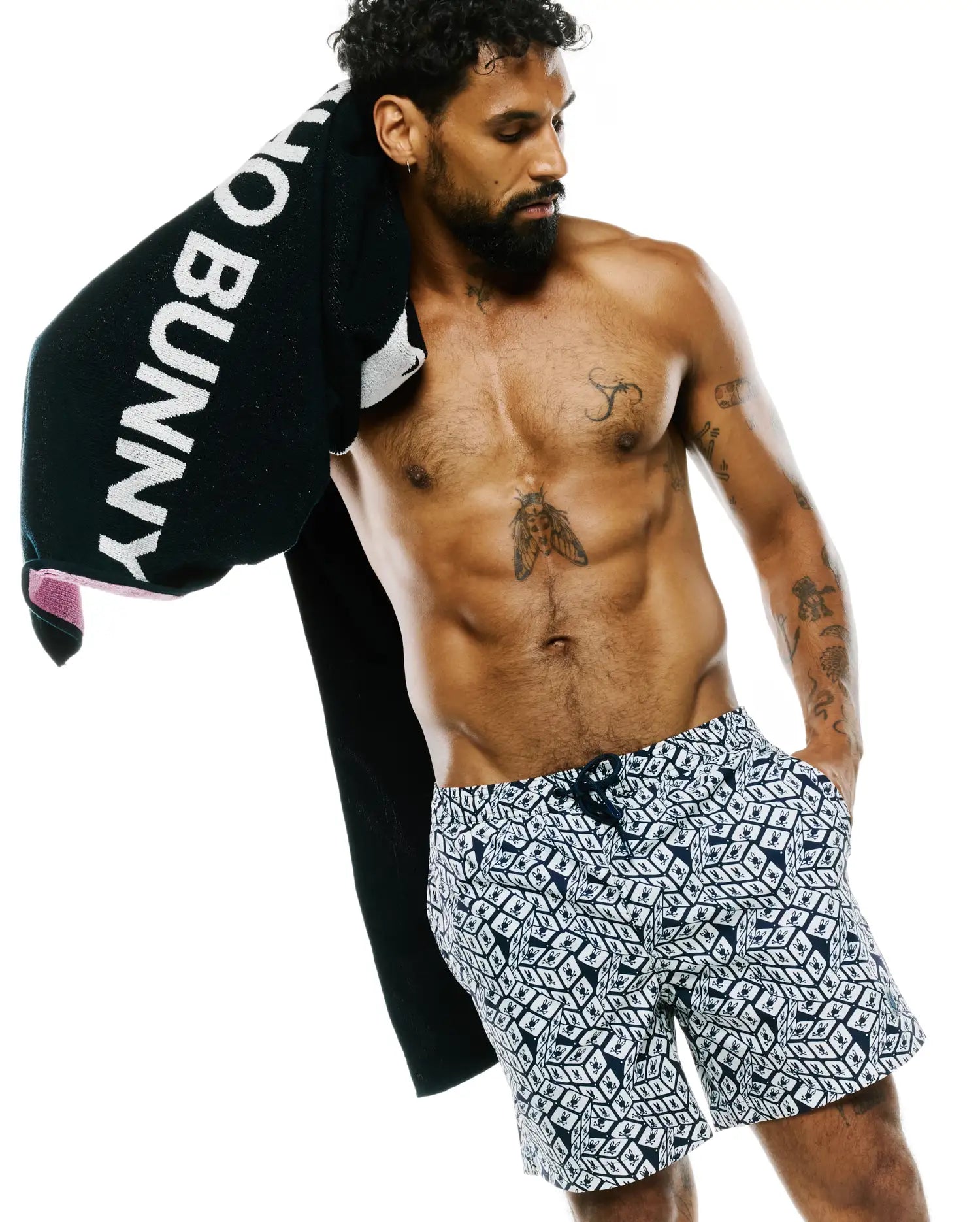Mens Eddy All Over Print Swim Trunk, a classic fit, navy and white design with an all-over geometric pattern featuring repeated small Psycho Bunny skull logos.