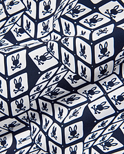 Mens Eddy All Over Print Swim Trunk, navy and white, featuring a repeating geometric cube pattern with the iconic Psycho Bunny skull logo on smooth fabric.