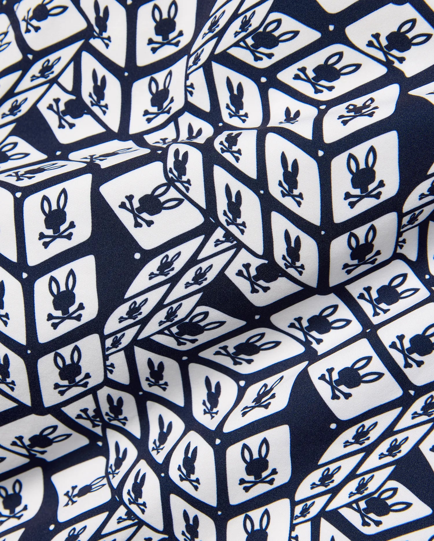 Mens Eddy All Over Print Swim Trunk, navy and white, featuring a repeating geometric cube pattern with the iconic Psycho Bunny skull logo on smooth fabric.