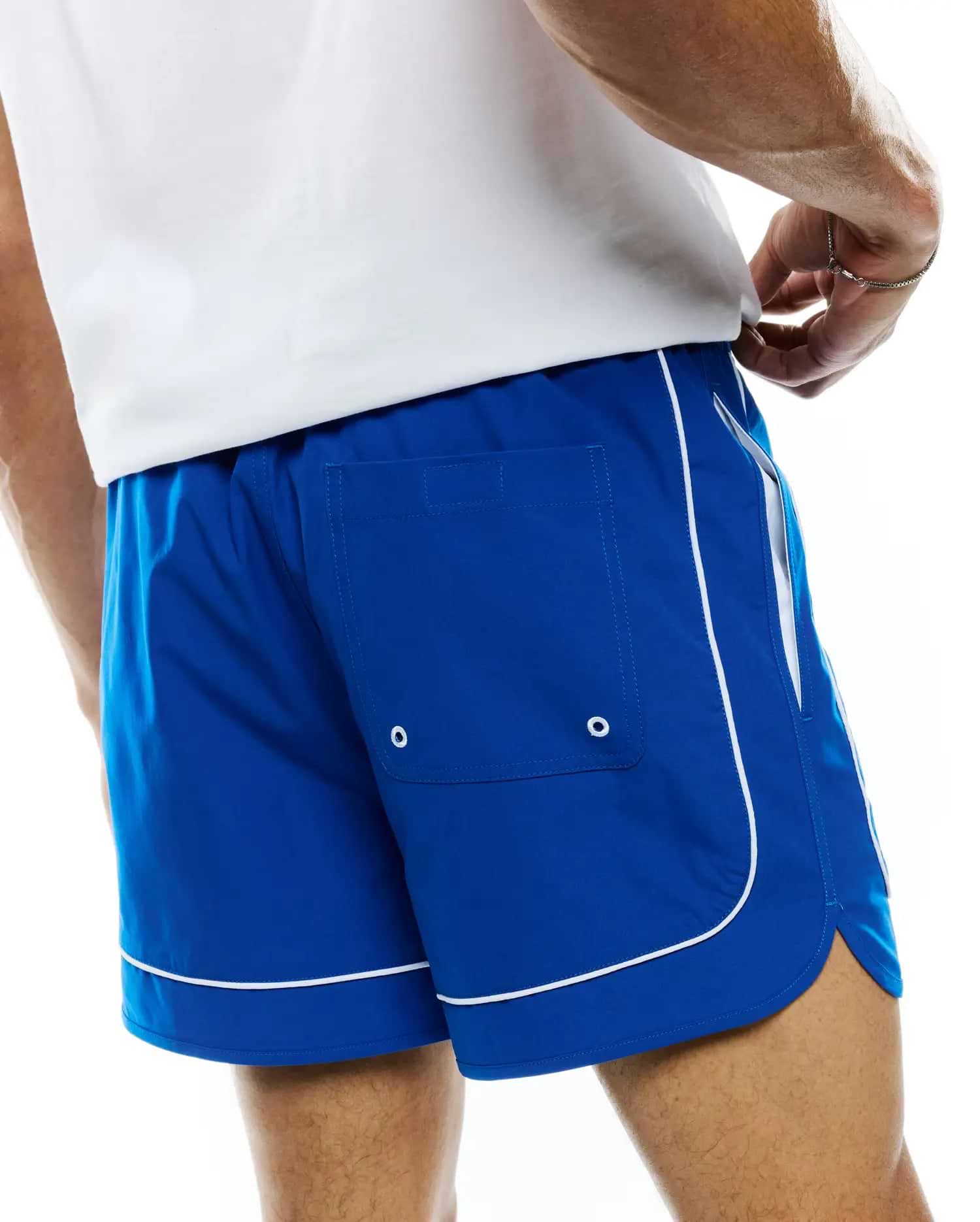 Mens Nathaniel Swim Trunk in vibrant royal blue, featuring white side stripes, piping, a back pocket with two grommets, and a curved hem, crafted from smooth, quick-dry fabric.