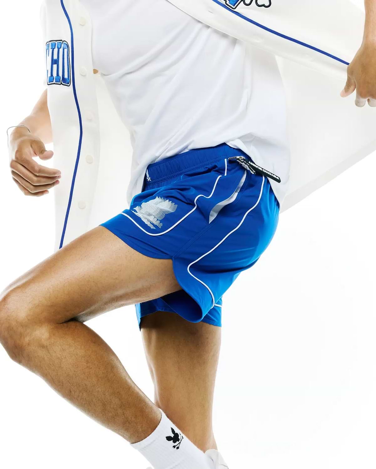 Mens Nathaniel Swim Trunk in royal blue, featuring white side piping, a white Psycho Bunny skull graphic on the left leg, and a black Psycho Bunny branded drawstring, offering a slim, athletic fit in smooth, quick-dry fabric.