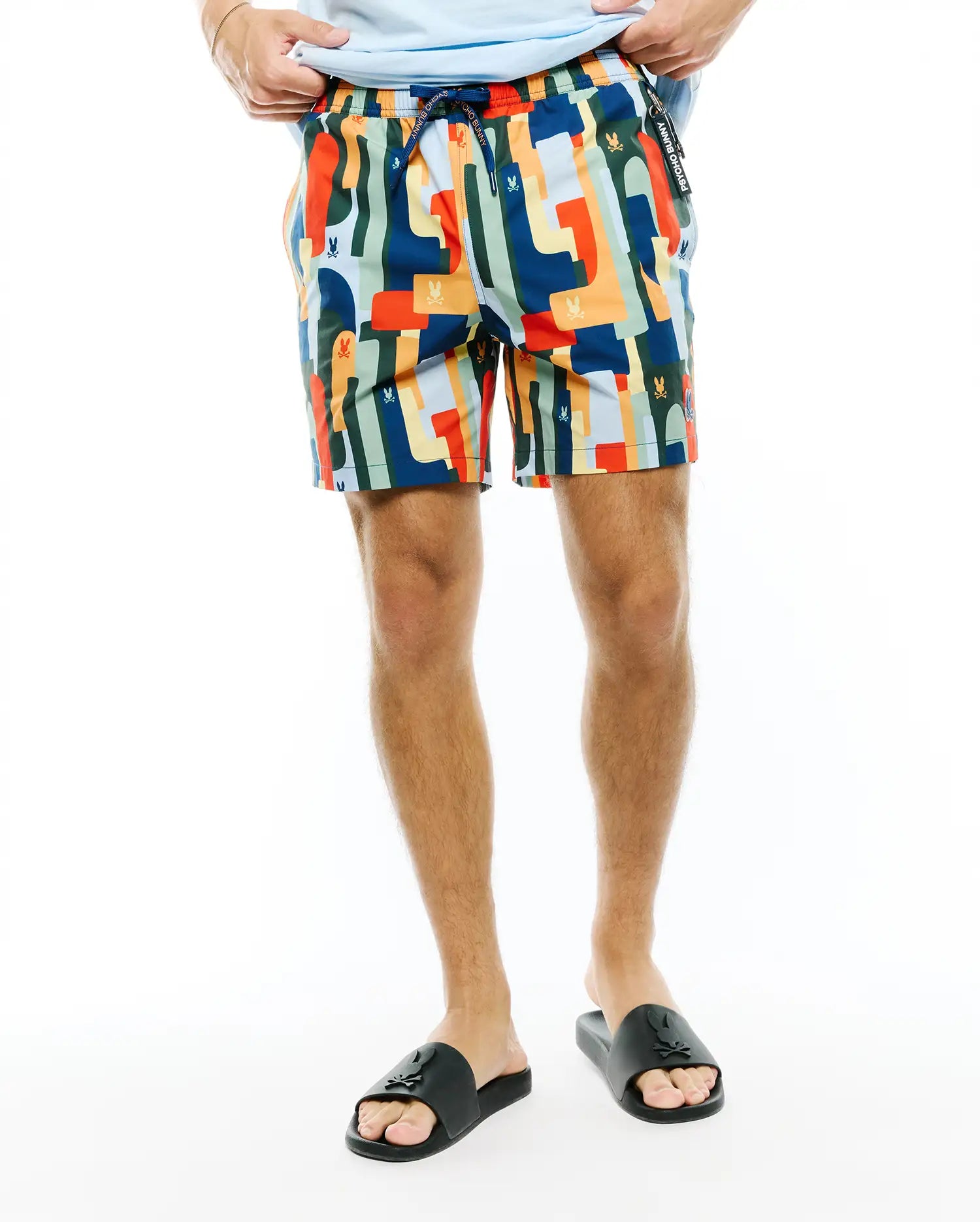 Mens Wes All Over Print Swim Trunk featuring a vibrant multi-color abstract geometric pattern with small integrated Psycho Bunny skull logos, a relaxed fit, and a branded drawstring waist.