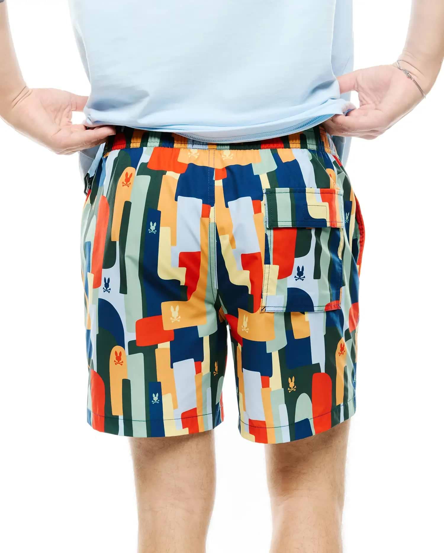 Mens Wes All Over Print Swim Trunk featuring a vibrant multi-color abstract pattern with repeated small Psycho Bunny skull logos, a relaxed fit, and a back flap pocket.