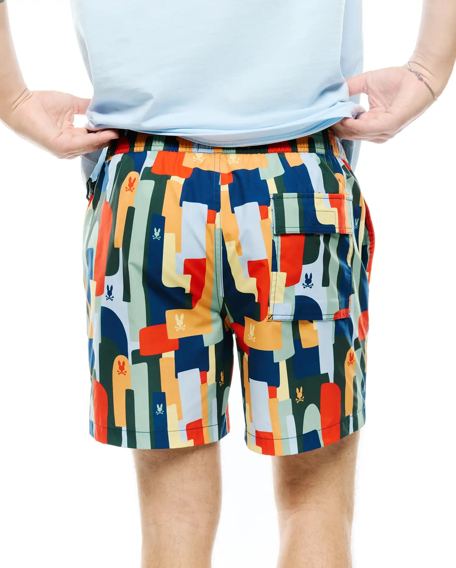 Mens Wes All Over Print Swim Trunk featuring a vibrant multi-color abstract pattern with repeated small Psycho Bunny skull logos, a relaxed fit, and a back flap pocket.