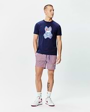 Navy blue jersey t-shirt with a large gradient Psycho Bunny skull logo on the chest, paired with Mens John All Over Print Swim Trunk featuring red, white, and navy vertical stripes and a small embroidered bunny logo.