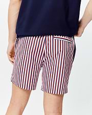 Mens John All Over Print Swim Trunk, a classic fit with vibrant vertical stripes in white, red, and navy blue, featuring a small striped back pocket on smooth fabric.