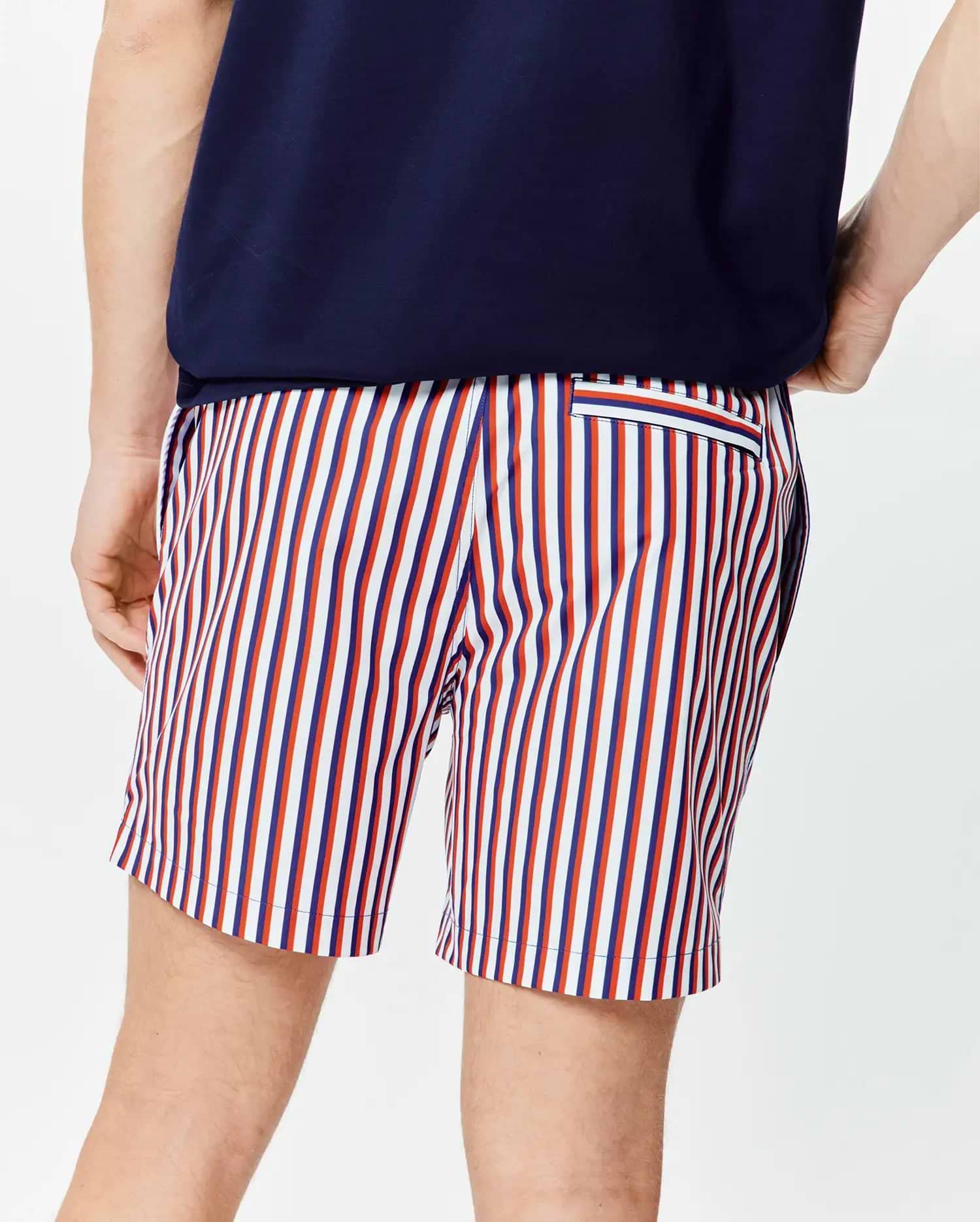 Mens John All Over Print Swim Trunk, a classic fit with vibrant vertical stripes in white, red, and navy blue, featuring a small striped back pocket on smooth fabric.