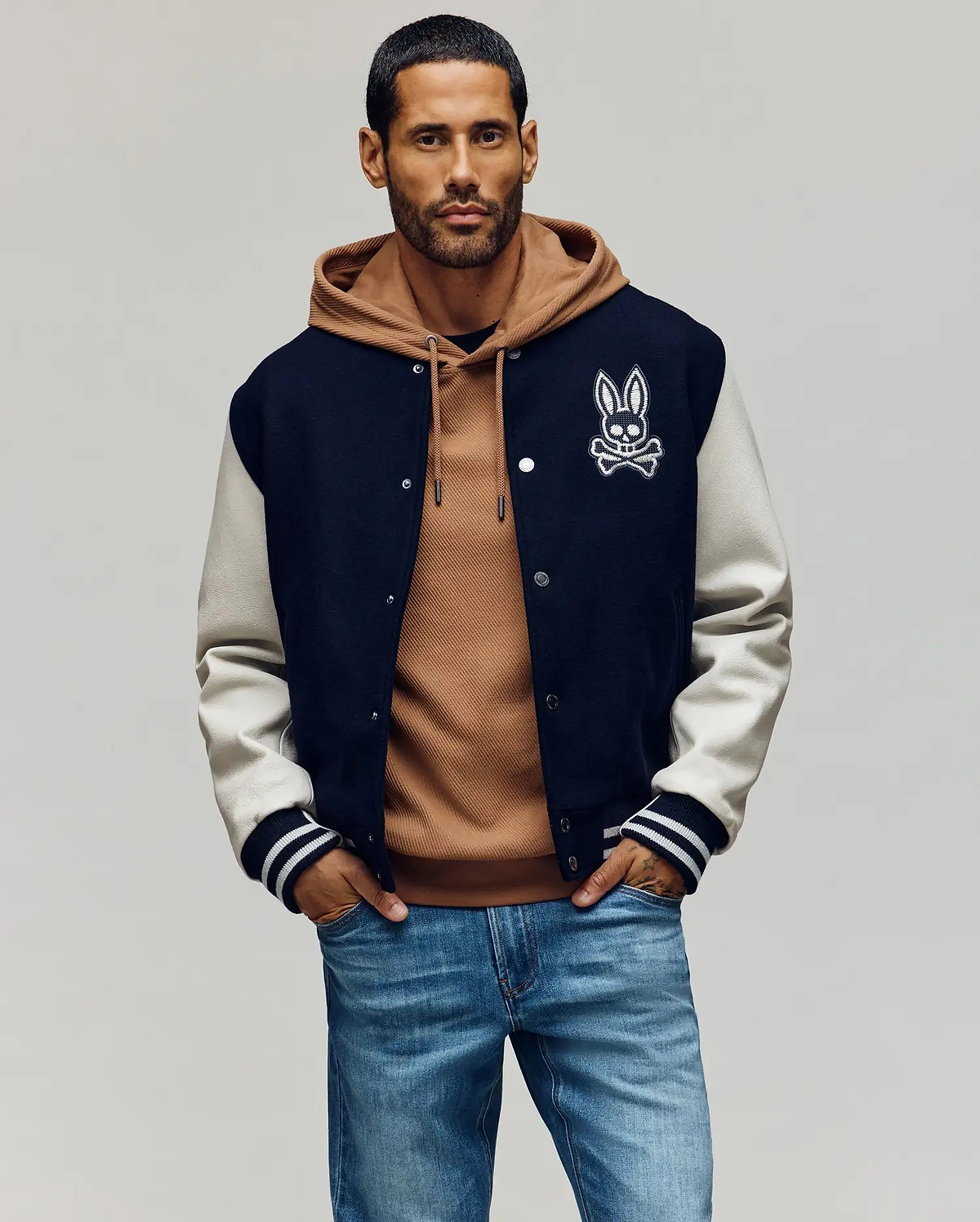 Mens Jacob Leather Bomber in classic fit, featuring a navy wool blend body with cream leather sleeves, snap closure, and ribbed cuffs. A large white embroidered Psycho Bunny skull logo adorns the left chest.