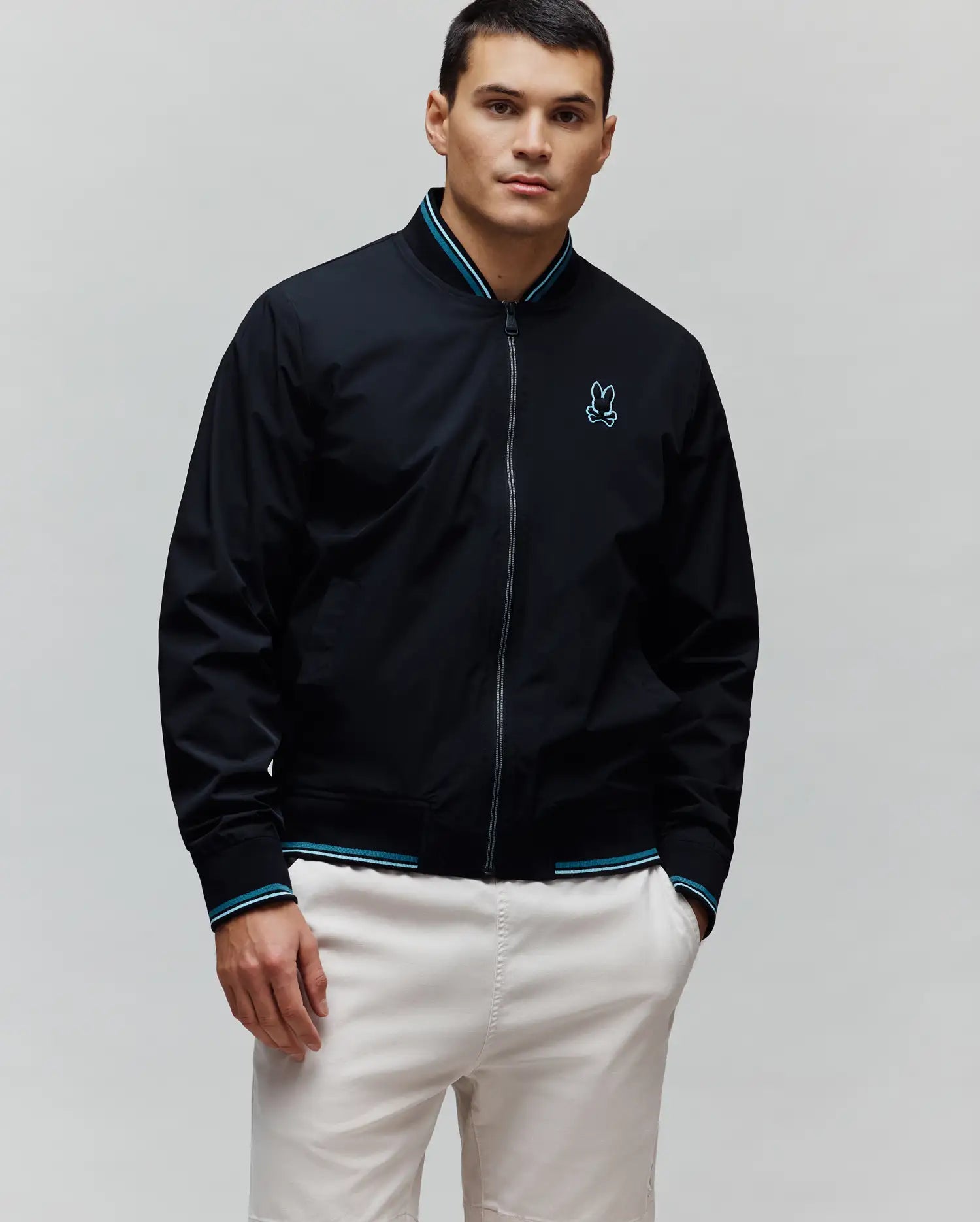 Black Mens Aldrin Bomber jacket, classic fit, featuring a full zip, teal and white striped ribbed collar and cuffs, and an embroidered light blue Psycho Bunny skull logo on the left chest.