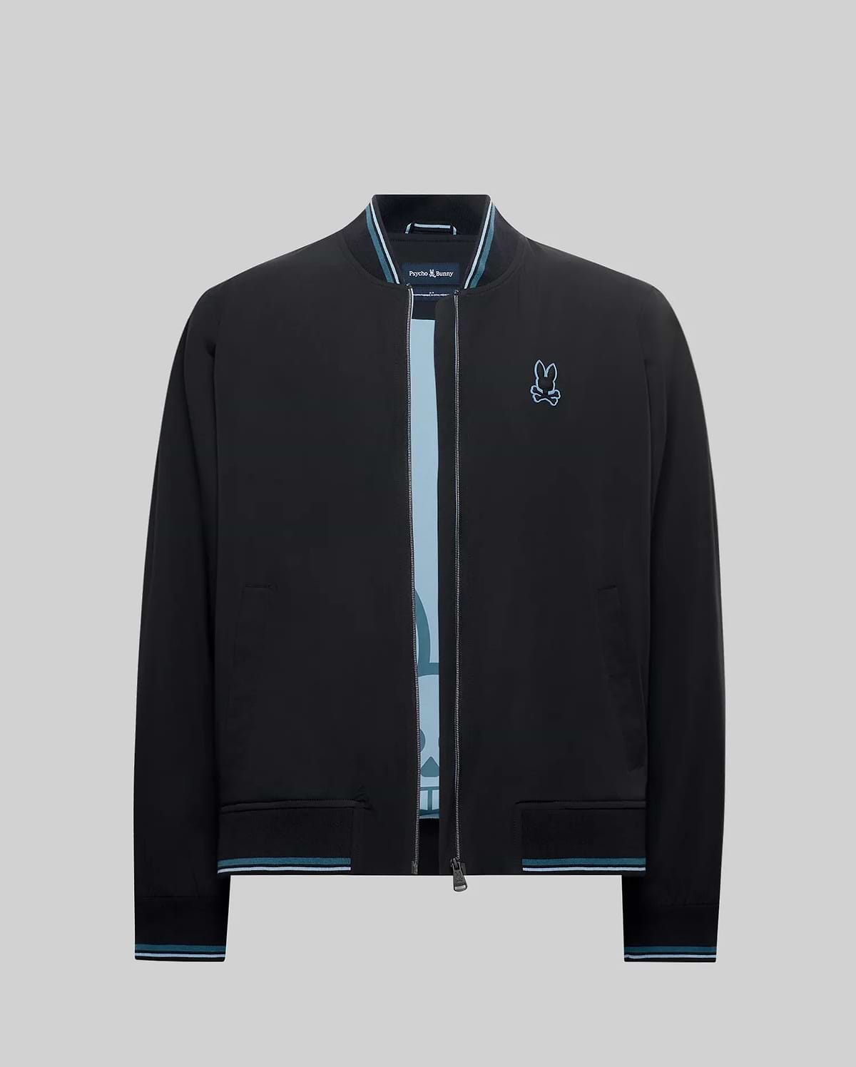 Mens Aldrin Bomber jacket in black, featuring a classic fit, smooth fabric, light blue and white striped ribbed collar, cuffs, and hem, with a small embroidered light blue Psycho Bunny skull logo on the left chest.