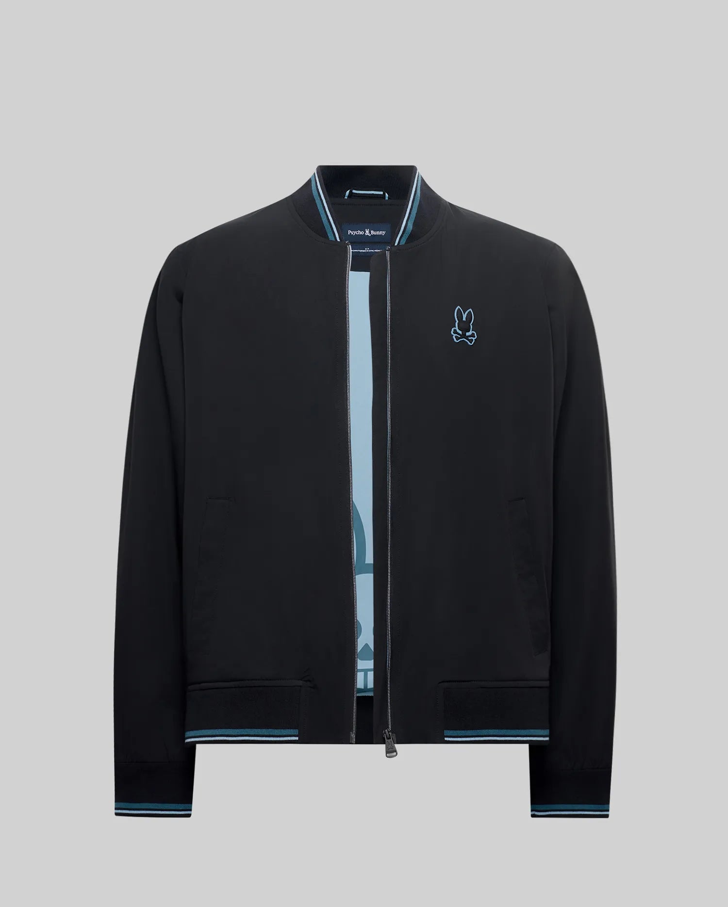 Mens Aldrin Bomber jacket in black, featuring a classic fit, smooth fabric, light blue and white striped ribbed collar, cuffs, and hem, with a small embroidered light blue Psycho Bunny skull logo on the left chest.
