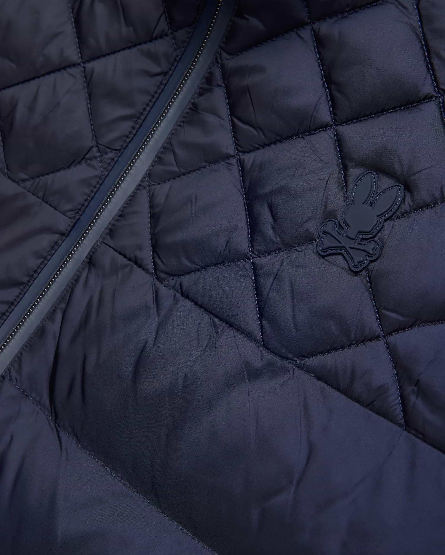 Mens Emerik Puffer Jacket, a navy quilted puffer jacket crafted from smooth nylon, featuring a dark zipper and a small, rubberized Psycho Bunny skull logo on the chest.