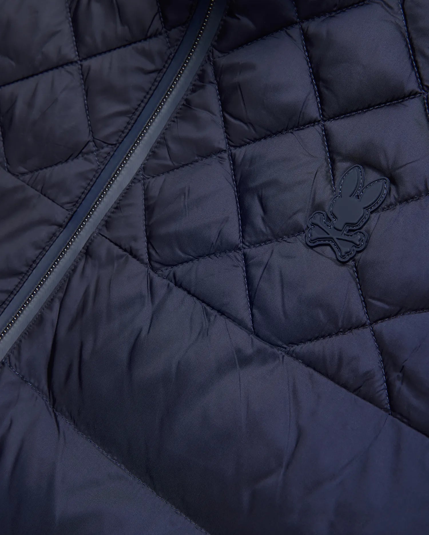 Mens Emerik Puffer Jacket, a navy quilted puffer jacket crafted from smooth nylon, featuring a dark zipper and a small, rubberized Psycho Bunny skull logo on the chest.