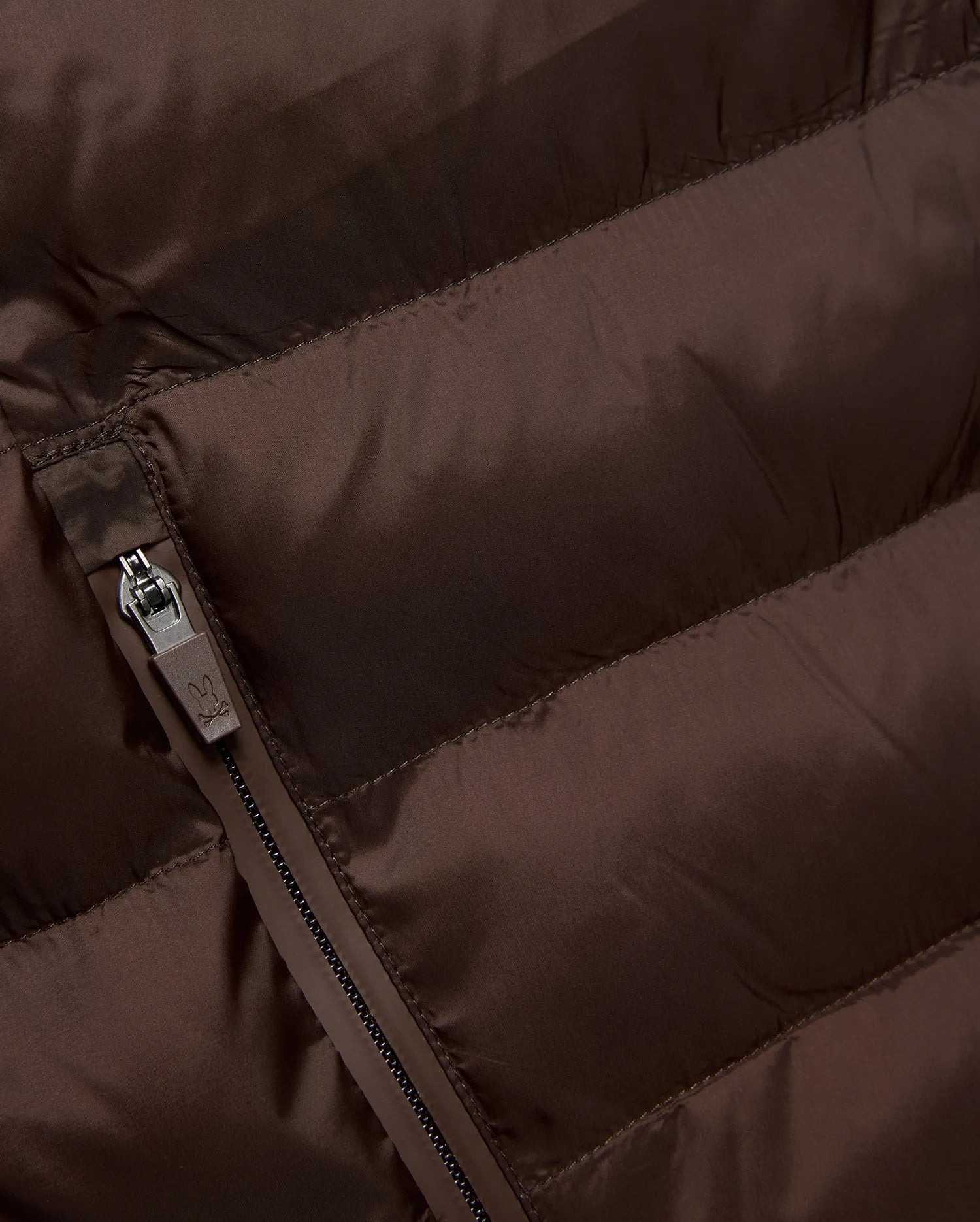 Mens Emerik Puffer Jacket in rich brown, crafted from smooth, quilted nylon. Features horizontal puffer channels and a dark grey zipper with a small Psycho Bunny skull logo pull.