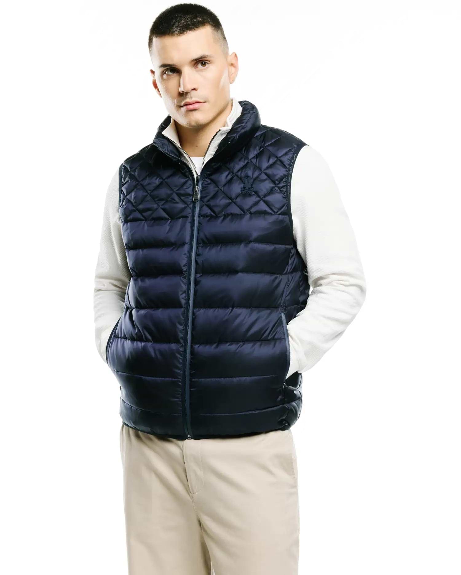Mens Emerik Quilted Puffer Vest in navy blue, featuring a classic fit, full-zip front, stand collar with white lining, diamond and horizontal quilting, and a small embroidered Psycho Bunny skull logo on the left chest.