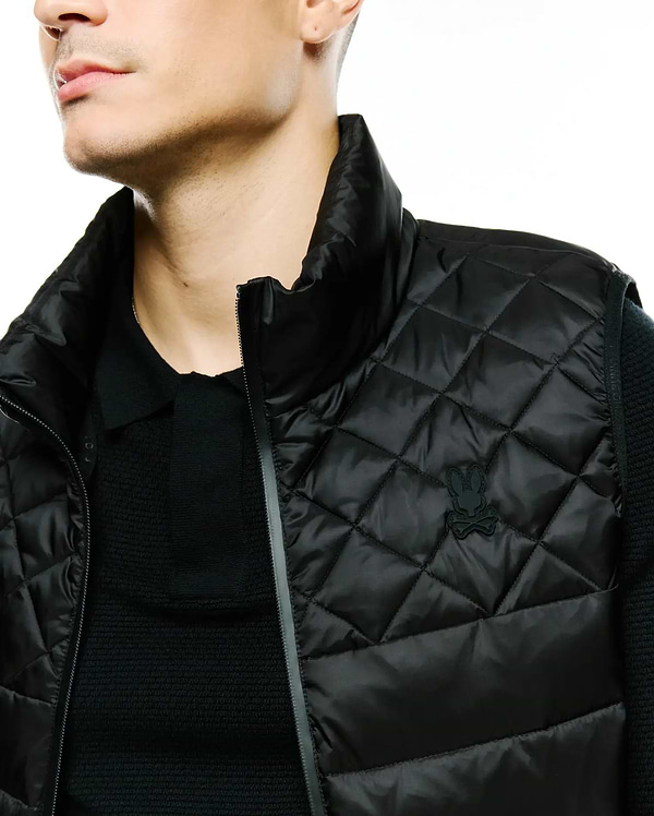 MENS EMERIK QUILTED PUFFER VEST, a black classic fit puffer vest featuring a diamond quilted pattern, stand-up collar, and a small tonal black Psycho Bunny skull logo on the left chest.