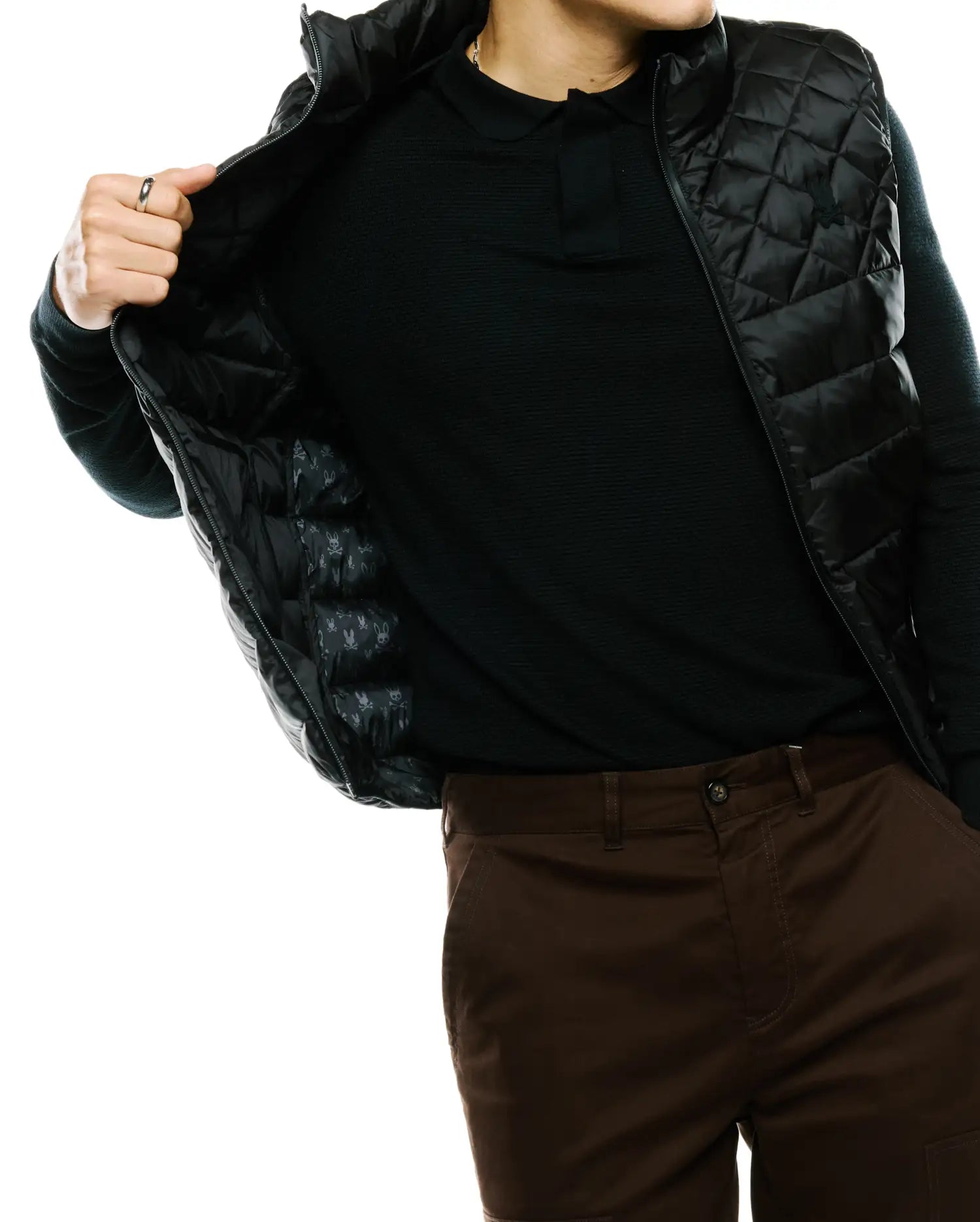 Mens Emerik Quilted Puffer Vest, black with a diamond quilted pattern, full zip, and small embroidered Psycho Bunny skull logo on the chest. Inner lining features a repeating skull logo pattern.