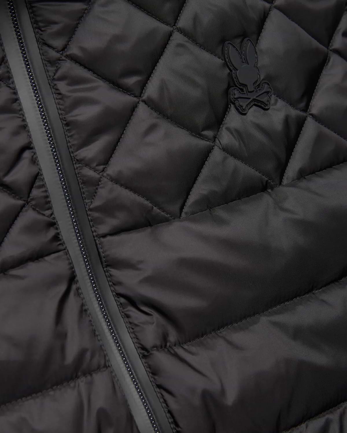 Mens Emerik Puffer Vest in black, featuring a quilted smooth nylon fabric, full-zip closure, and a small, tonal rubberized Psycho Bunny skull logo on the left chest.