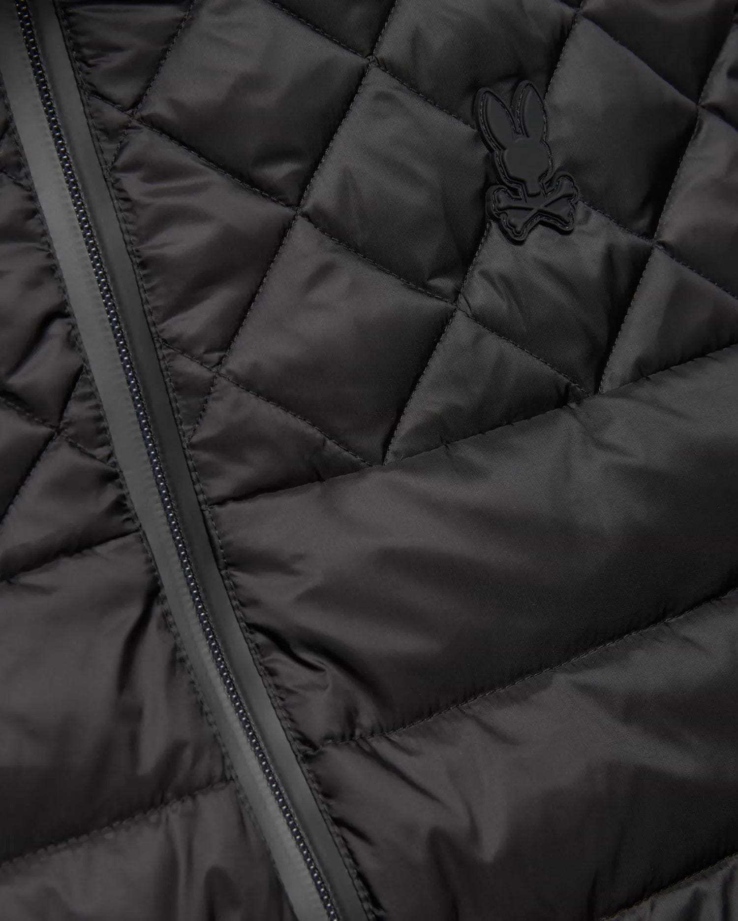 Mens Emerik Puffer Vest in black, featuring a quilted smooth nylon fabric, full-zip closure, and a small, tonal rubberized Psycho Bunny skull logo on the left chest.