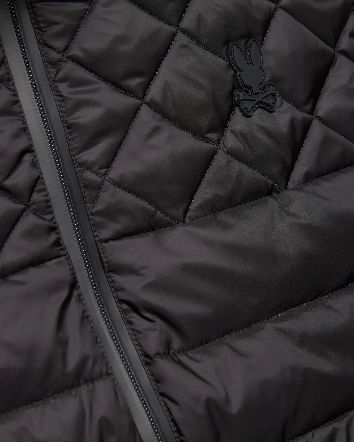 Mens Emerik Puffer Vest in black, featuring a quilted smooth nylon fabric, full-zip closure, and a small, tonal rubberized Psycho Bunny skull logo on the left chest.