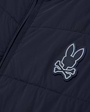 Mens Gordley Mix Media Jacket in navy blue, featuring a quilted left panel and smooth right panel, with a prominent Psycho Bunny skull and crossbones logo on the chest, detailed with white and light blue accents and embossed brand lettering. (5)