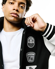Mens Reilly Knit Coach Jacket, black with white sleeves, features multiple embroidered Psycho Bunny skull patches on the chest, ribbed cuffs with white stripes, and a classic fit. (3)