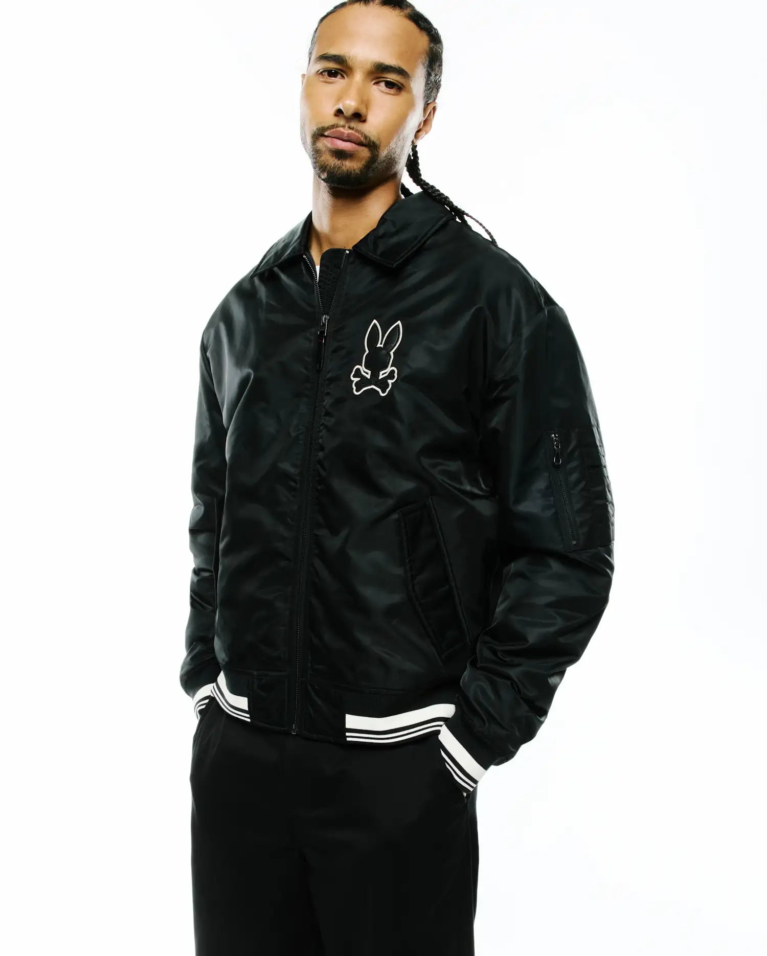 Mens Nathaniel Satin Coach Jacket, black with a relaxed fit, featuring a shiny satin texture, full zip, classic collar, white striped ribbed cuffs and hem, and a large white embroidered Psycho Bunny skull logo on the left chest. (2)