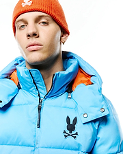 Men's Solan Puffer Jacket in bright blue with a contrasting orange hood lining, featuring a large black Psycho Bunny skull logo on the left chest and a full zip closure. (2)