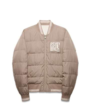 Men's Franco Reversible Bomber, a beige quilted jacket with white striped ribbed collar, cuffs, and hem, featuring a large embroidered Psycho Bunny text and skull logo patch on the left chest. (5)