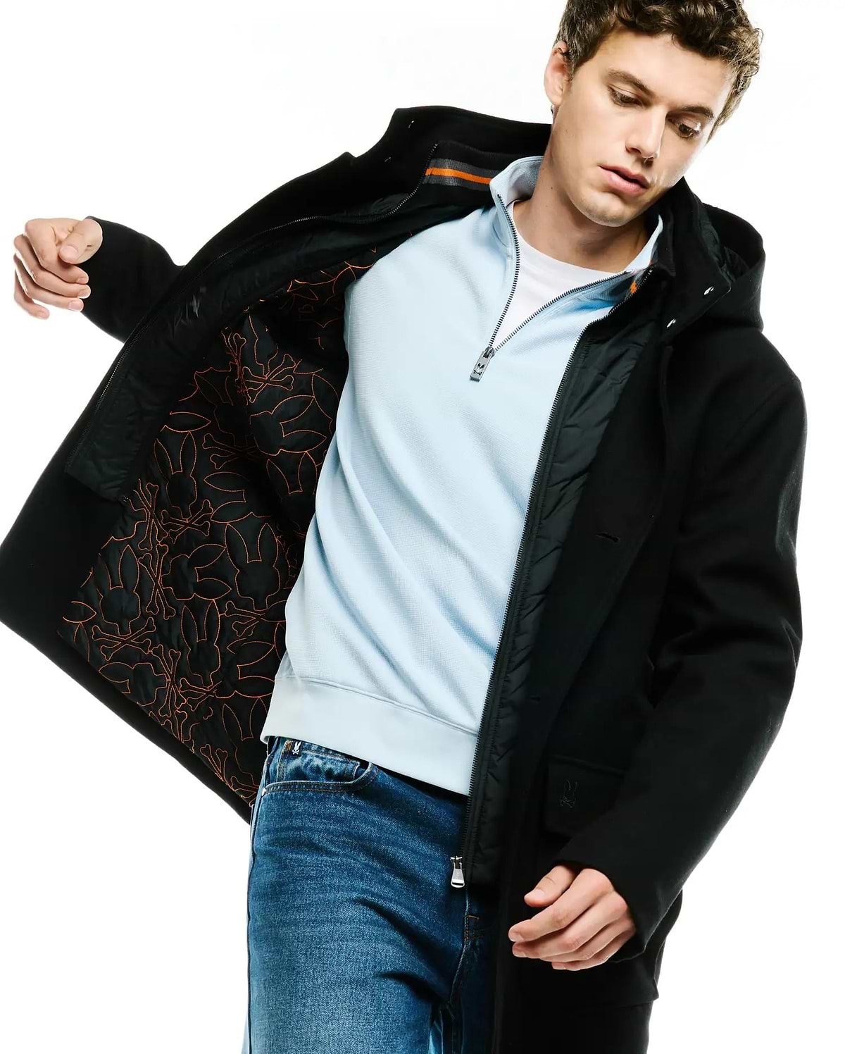MENS LUTHER WOOL BLEND COAT, a black hooded classic fit coat with button closure, featuring a quilted black lining with an orange Psycho Bunny skull and crossbones pattern and a small embroidered logo on the sleeve.
