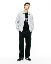 Mens Marc Textured Overshirt in light grey, featuring a subtle textured fabric, classic collar, and a single chest pocket, worn over a black t-shirt with a large white Psycho Bunny skull and crossbones graphic. (5)