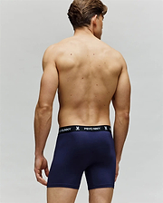 A man faces away from the camera wearing Psycho Bunny’s MENS 3 PACK BOXER BRIEF - MO1400006 in navy, crafted from a cotton-modal blend with a black waistband and white branding. His back and arms are visible against a plain light background.