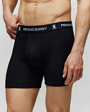 A man wears Psycho Bunny’s MENS 3 PACK BOXER BRIEF - MO1400006, featuring the brand's logo and bunny graphic on the waistband, made from a cotton-modal blend. Only his torso and upper legs are visible against a plain light background.