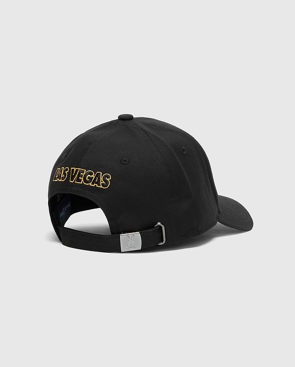 The Psycho Bunny MENS LAS VEGAS BASEBALL CAP (MO1500011) is a black, 100% cotton hat with gold "Las Vegas" embroidery on the back, direct embroidery, and an adjustable strap with a metal buckle. Made in China, it stands out beautifully against a plain white background.