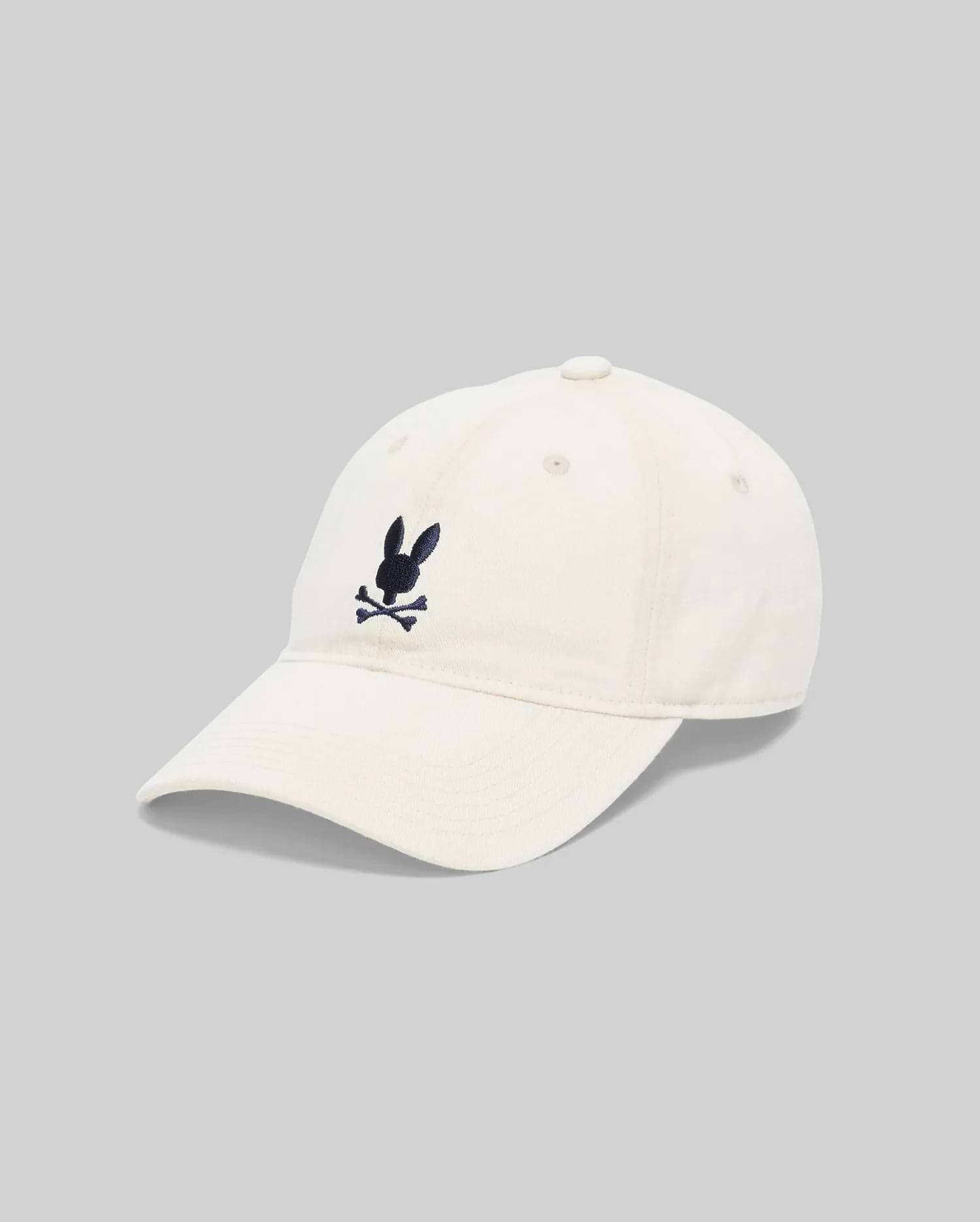 Jimmy Baseball Cap in cream cotton twill, featuring a classic fit and a medium-sized, embroidered navy blue Psycho Bunny skull logo centered on the front.