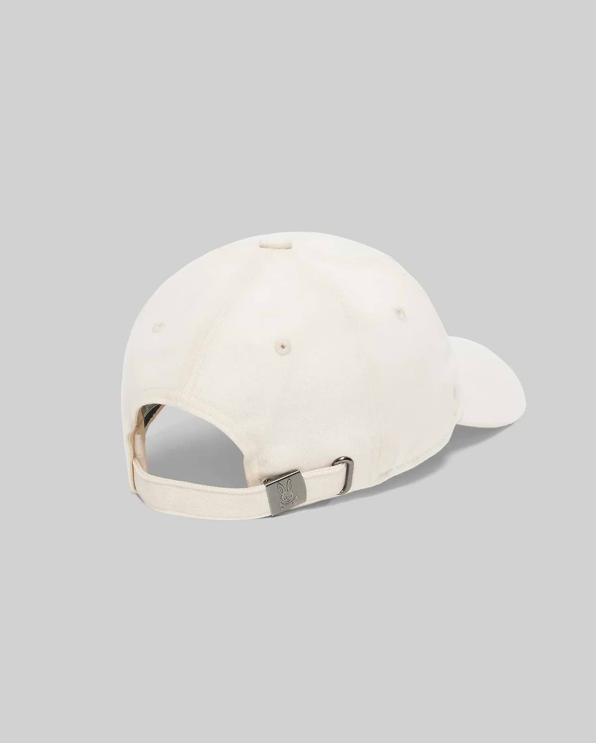 Jimmy Baseball Cap in cream cotton twill, featuring an adjustable strap and a gunmetal buckle with an engraved Psycho Bunny skull logo.
