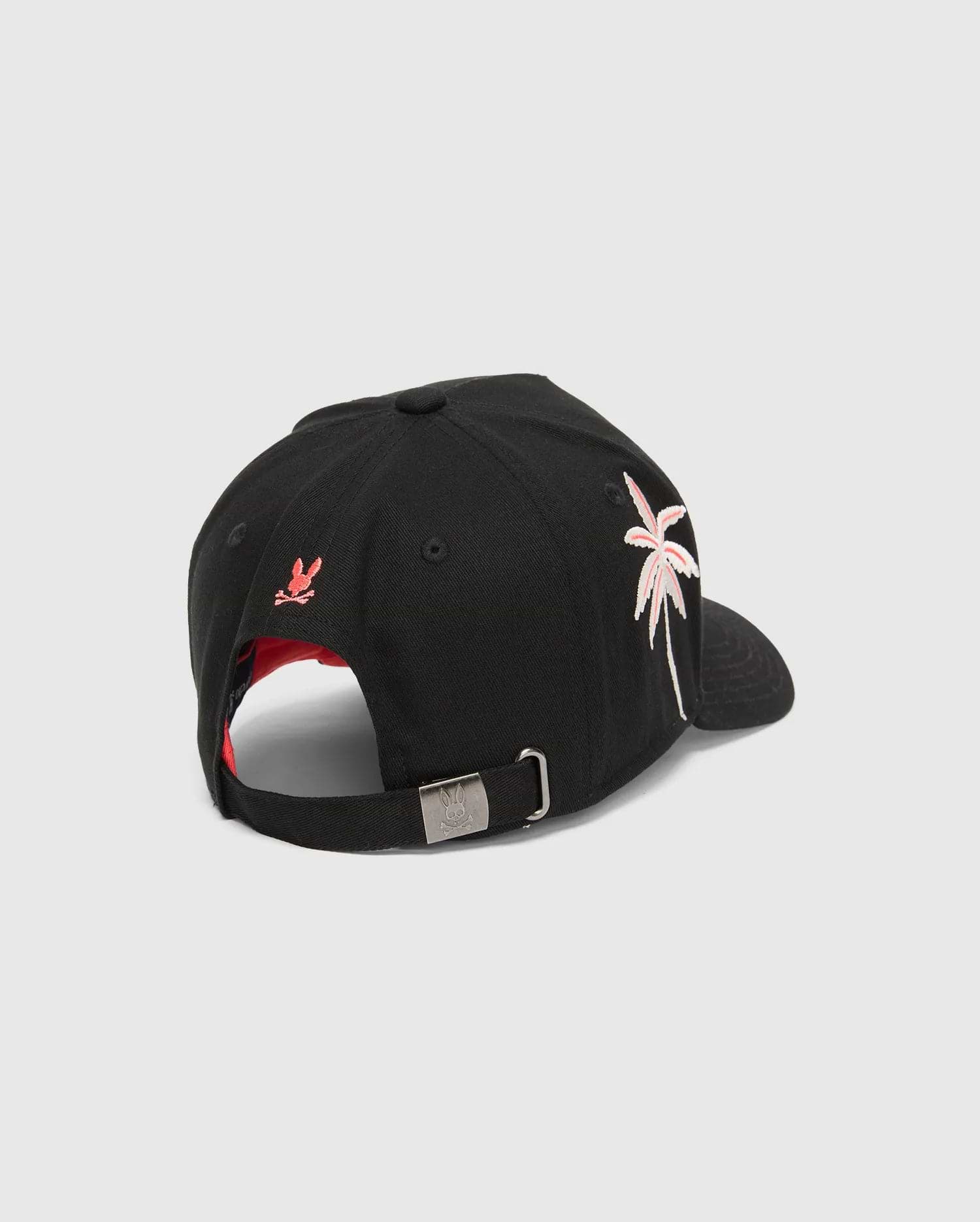 Black Mens Brad Trucker Cap with red underbrim, featuring an embroidered pink and white palm tree on the side, a small red Psycho Bunny skull on the back, and an engraved bunny skull on the metal buckle.