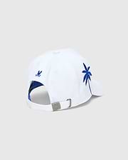 White Mens Brad Trucker Cap with blue interior, featuring a vibrant blue embroidered palm tree on the side, a small blue embroidered Psycho Bunny skull on the back, and a branded metal buckle.