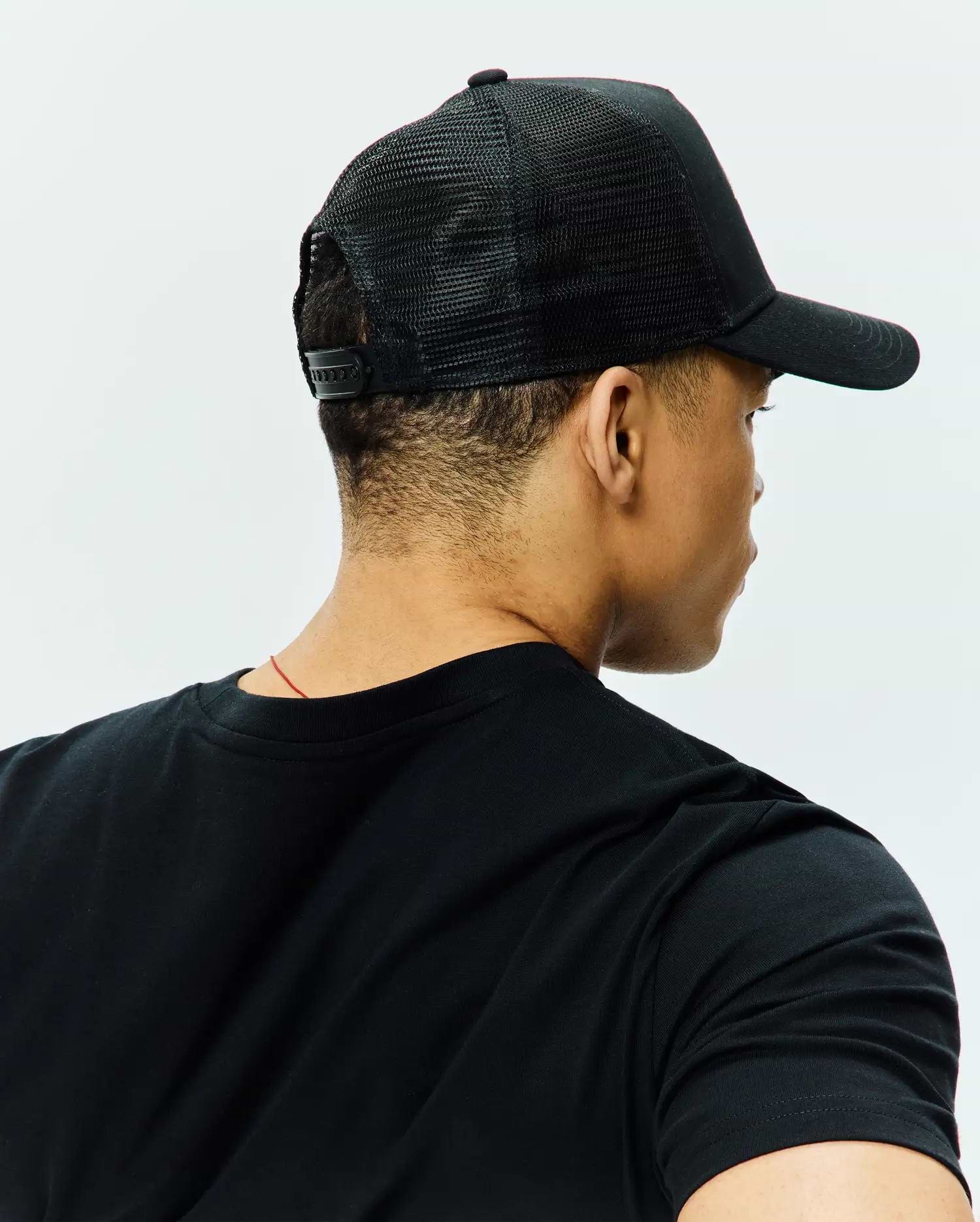 Black classic fit jersey t-shirt with a crew neck, paired with a black Mens Tobias Trucker Cap featuring a breathable mesh back and adjustable snap closure.