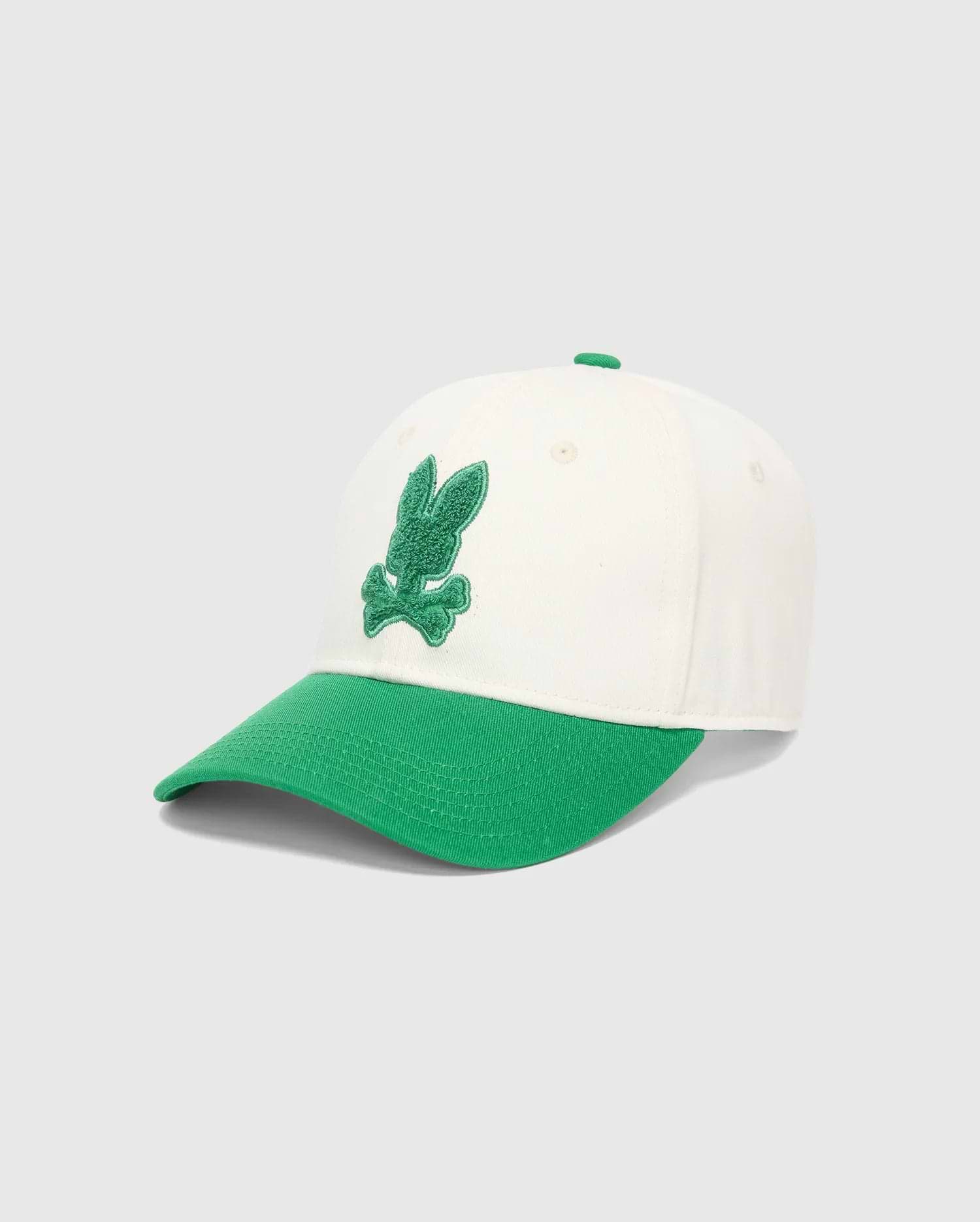 Mens Craig Baseball Cap in cream cotton twill with a vibrant green brim and matching top button, featuring a prominent, textured green embroidered Psycho Bunny skull logo on the front.
