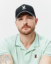 Mens Blaze Sport Cap, black with white Psycho Bunny logo and light blue brim trim. Mint green classic fit pique polo shirt features multi-color Psycho Bunny logo, navy trim, and orange shoulder stripes.